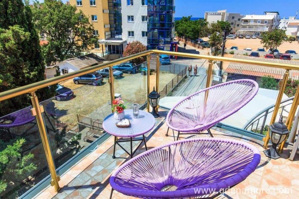 2 lila Stühle und ein Tisch auf dem Balkon in der Unterkunft Hotel Amon in Budva