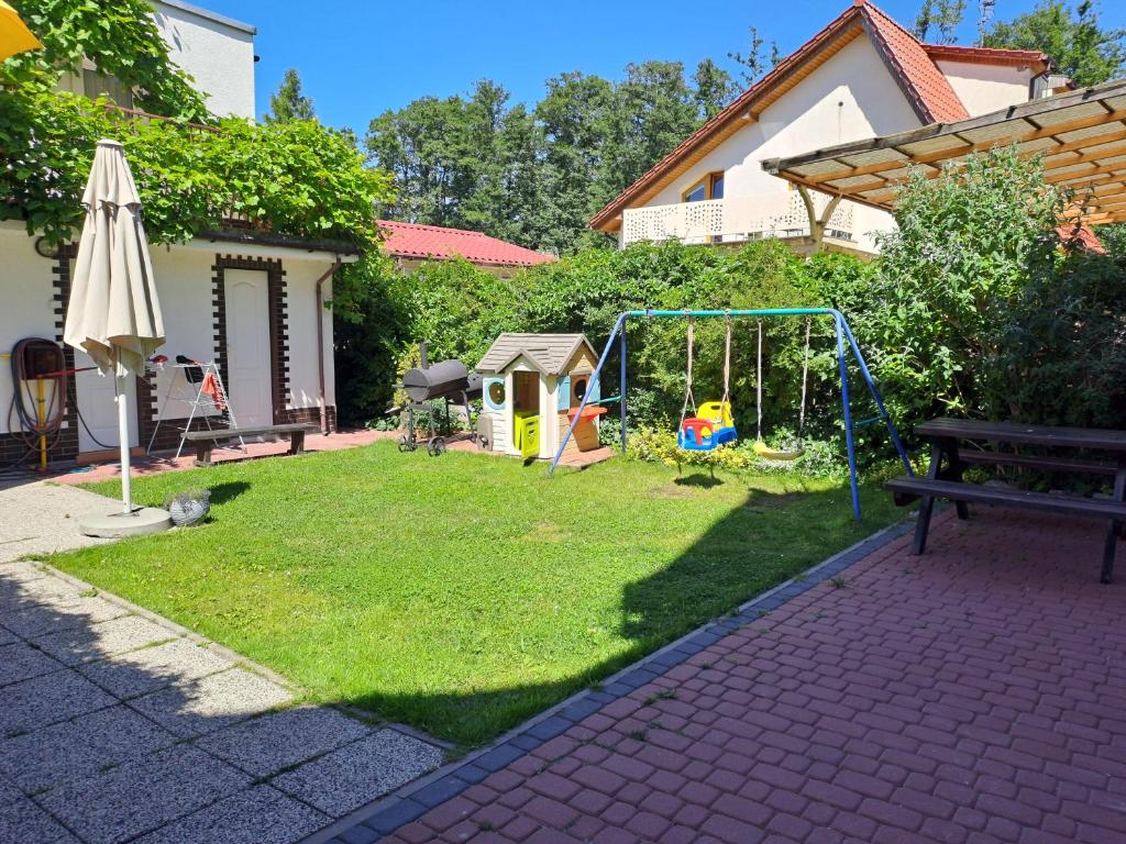a yard with a playground with a bench and an umbrella at Akwarium in Międzywodzie