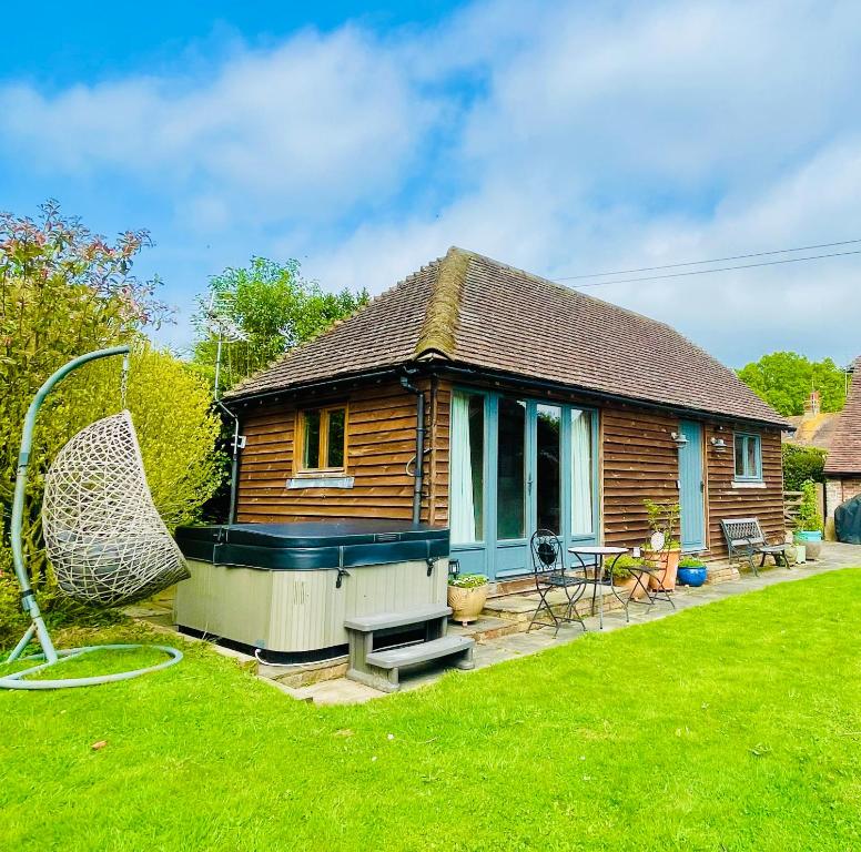 a small wooden house with a yard with a house at The Barn cottage with hot tub overlooking the lake in Ringmer