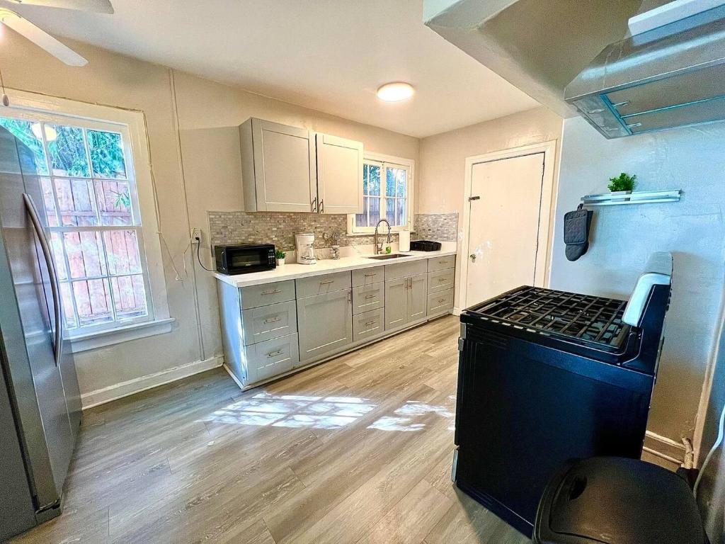 a kitchen with white cabinets and a black stove at Hollywood Gem 2 Bed Haven! in Los Angeles