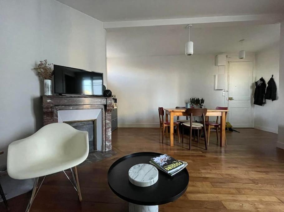 - un salon avec une cheminée, une table et des chaises dans l'établissement Parisian Nest - Comfort appartement, à Paris