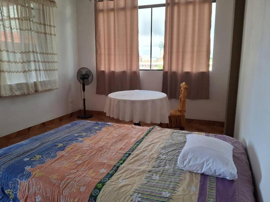 Un dormitorio con una cama y una mesa en una ventana en Disfruta la Selva Peruana Pto.M, en Puerto Maldonado