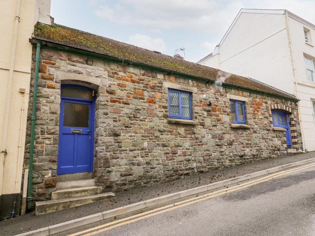 a brick building with a blue door on a street at Llys-Yr-Onnen in Carmarthen