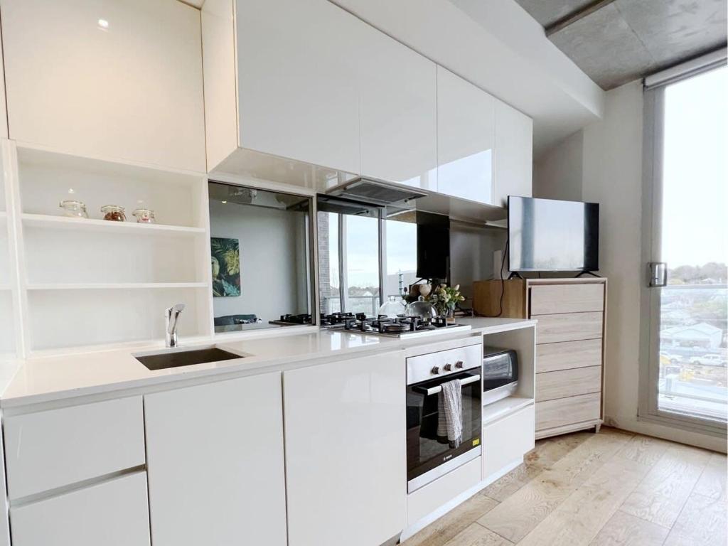 Apartment on Regent في ملبورن: مطبخ أبيض مع حوض وموقد