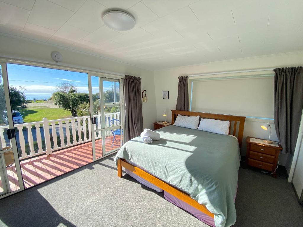 a bedroom with a large bed and a balcony at Coastal Charm in Patons Rock in Rangihaeata