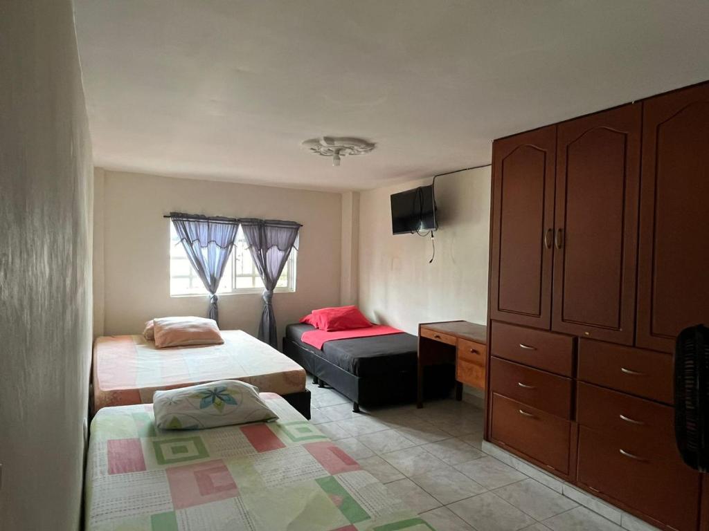 a small bedroom with two beds and a dresser at Hostal Jireth in Floridablanca