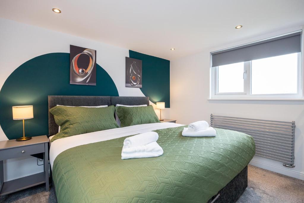 een slaapkamer met een groen bed met 2 handdoeken erop bij AvenueHouse-Airport-FREEParking&WIFI in Baguley