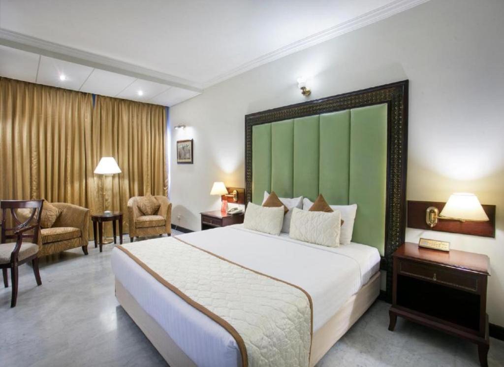 a hotel room with a large bed with a green headboard at Hotel ALVAA GRAND Near Delhi Airport BY-AERO HOME STAY in New Delhi