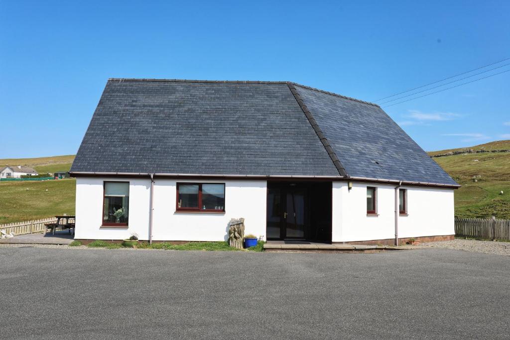 uma casa branca com um telhado preto em Corncrake Cottage em Manish