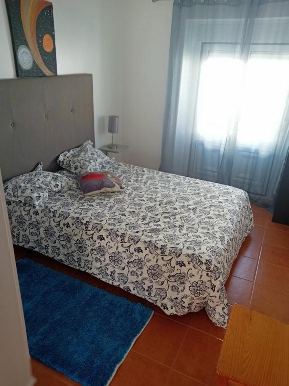 1 dormitorio con 1 cama con alfombra azul y ventana en Carolina do Mar, en Nazaré