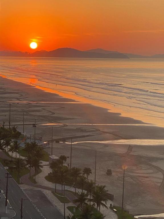 an orange sunset over the ocean with a beach at Apartamento de frente para o mar, 3 quartos in Solemar