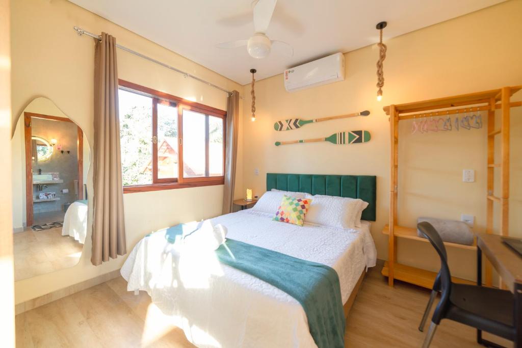 um quarto com uma cama, uma secretária e uma janela em Lofts Corujinha Paraty em Paraty