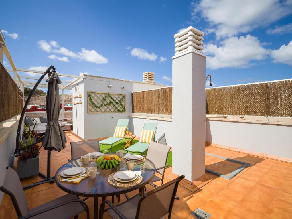 patio con tavolo e sedie sul tetto di Casa Maresía Penthouse - Pool & Beach a Sardina