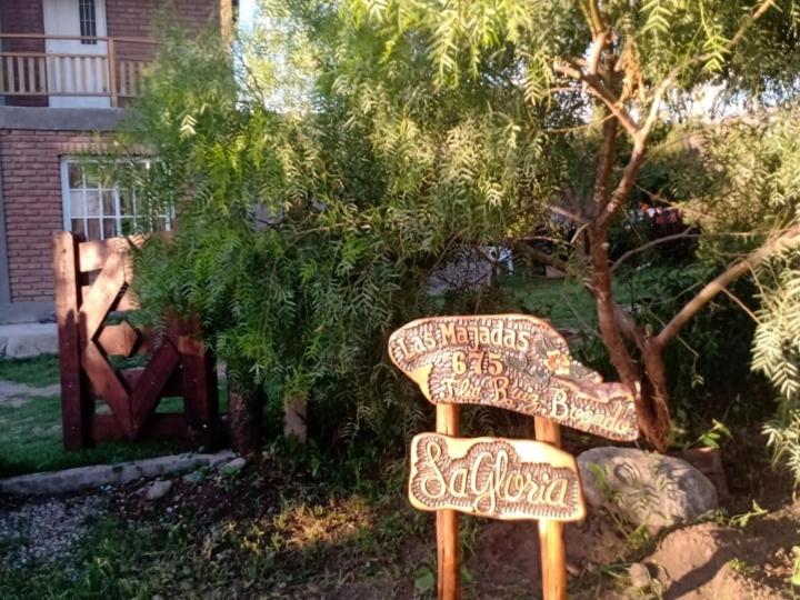 um sinal para um jardim com um banco num quintal em La Gloria em Merlo