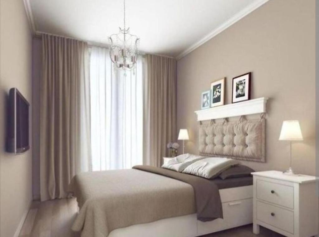 - une chambre avec un grand lit et un lustre dans l'établissement SUITES Corrientes, à Corrientes