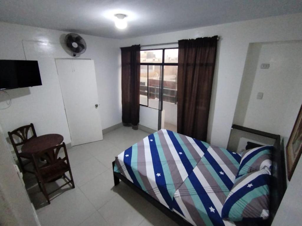 a bedroom with a bed and a chair and a window at THE ROYAL GUEST HOUSE Hco in Huanchaco