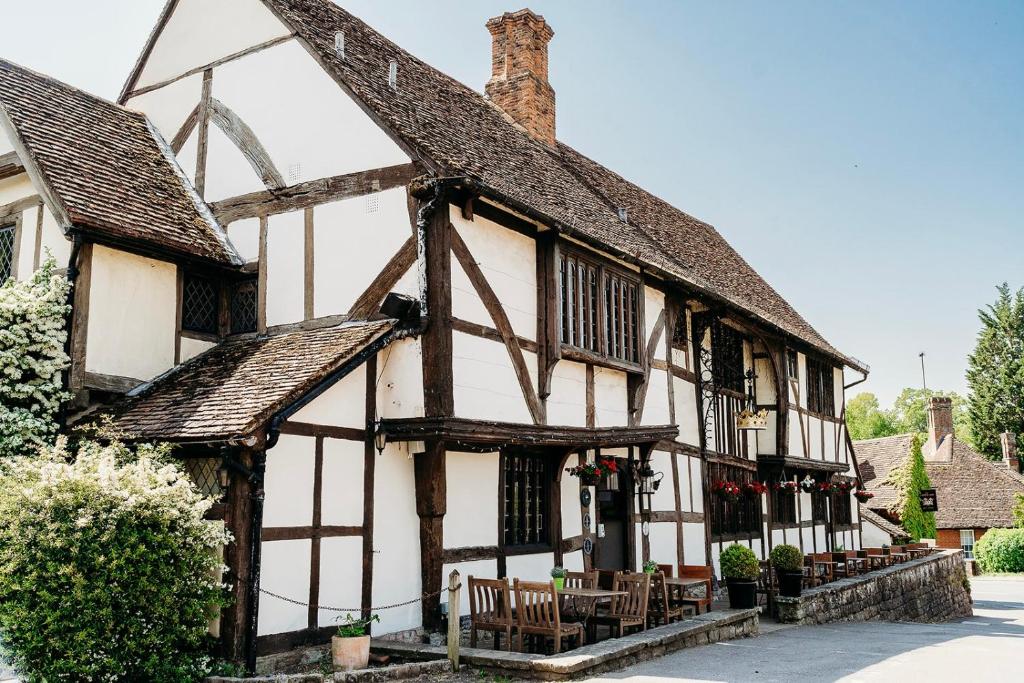 un antiguo edificio con mesas y sillas delante de él en The Crown Inn, en Chiddingfold