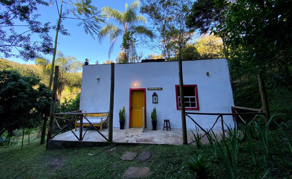 Chalé na floresta com frigobar في أورو بريتو: منزل صغير بباب اصفر في ساحة