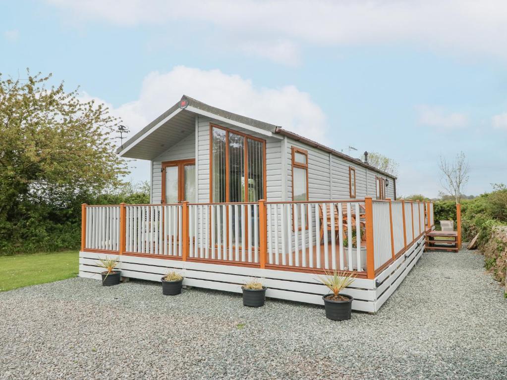 a tiny house with an orange and white fence at Y Caban in Llanfairpwllgwyngyll