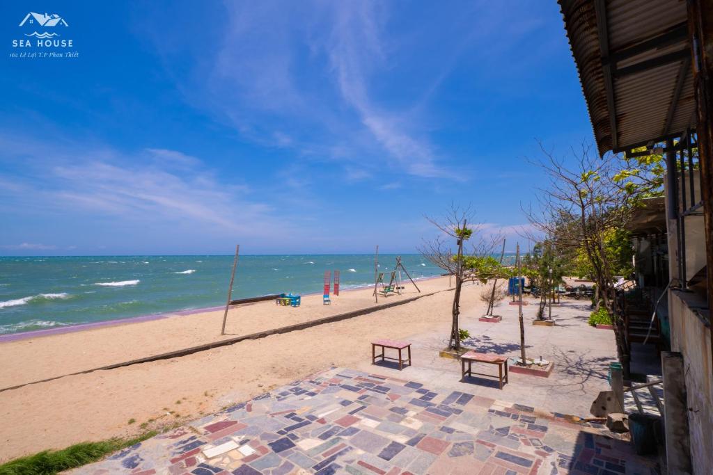 einen Sandstrand mit einer Bank und dem Meer in der Unterkunft Sea House in Ấp Bình Hưng