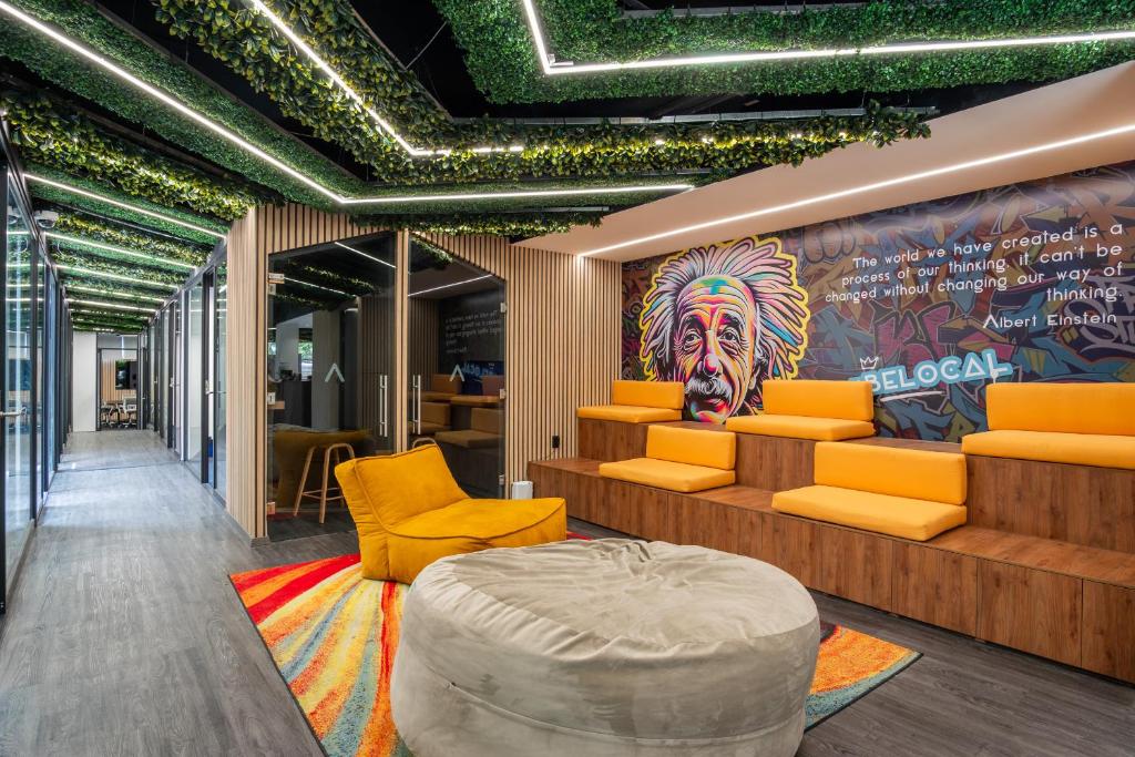 A colorful communal lounge with tiered orange seating and a mural.