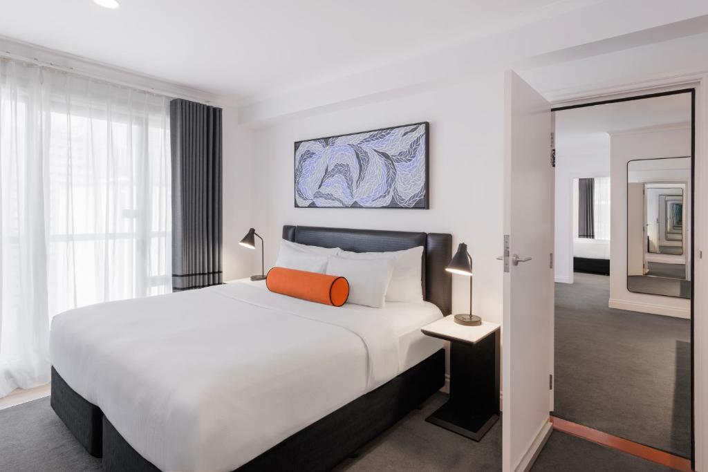 a bedroom with a large white bed with an orange pillow at CityLife Auckland in Auckland