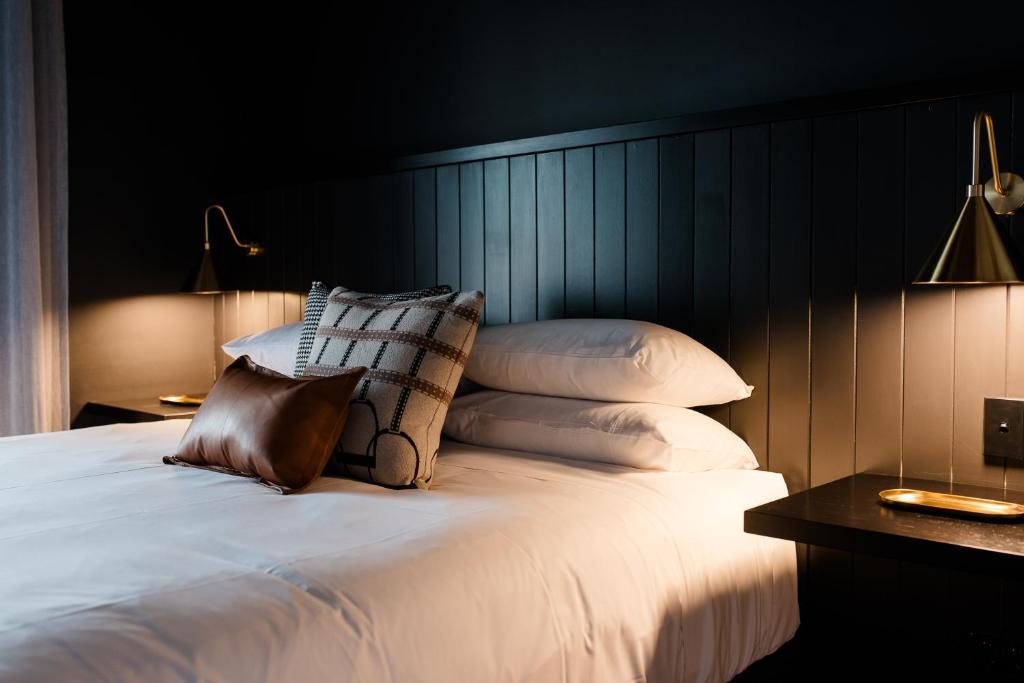 1 dormitorio con 1 cama blanca con almohadas y 2 lámparas en The Victoria Hotel Rutherglen, en Rutherglen