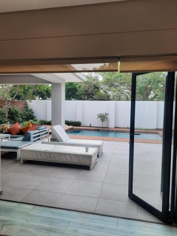 Luxury holiday home 3 bedroom, 3 bathroom house in Nahoon في شرق لندن: فناء به كنبتين بيضاء ومسبح