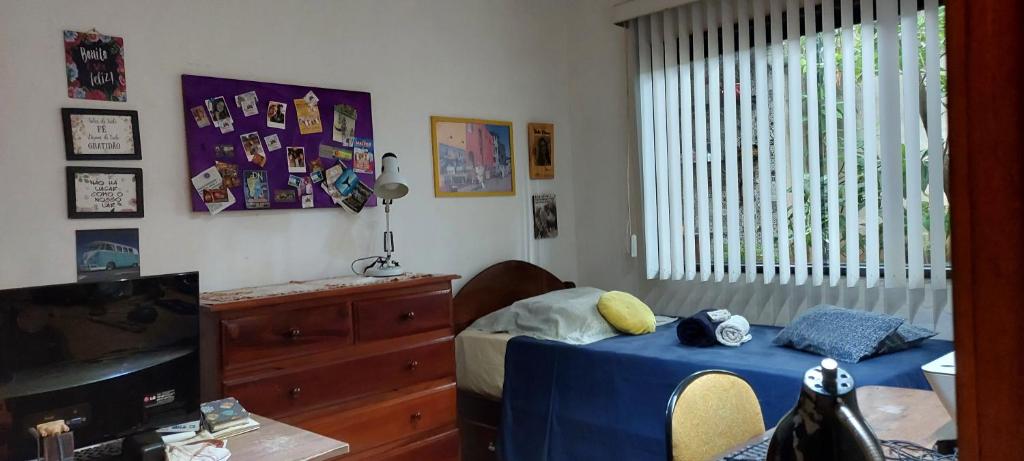 um quarto com uma cama, uma televisão e uma janela em Quarto em casa familiar. em Porto Velho