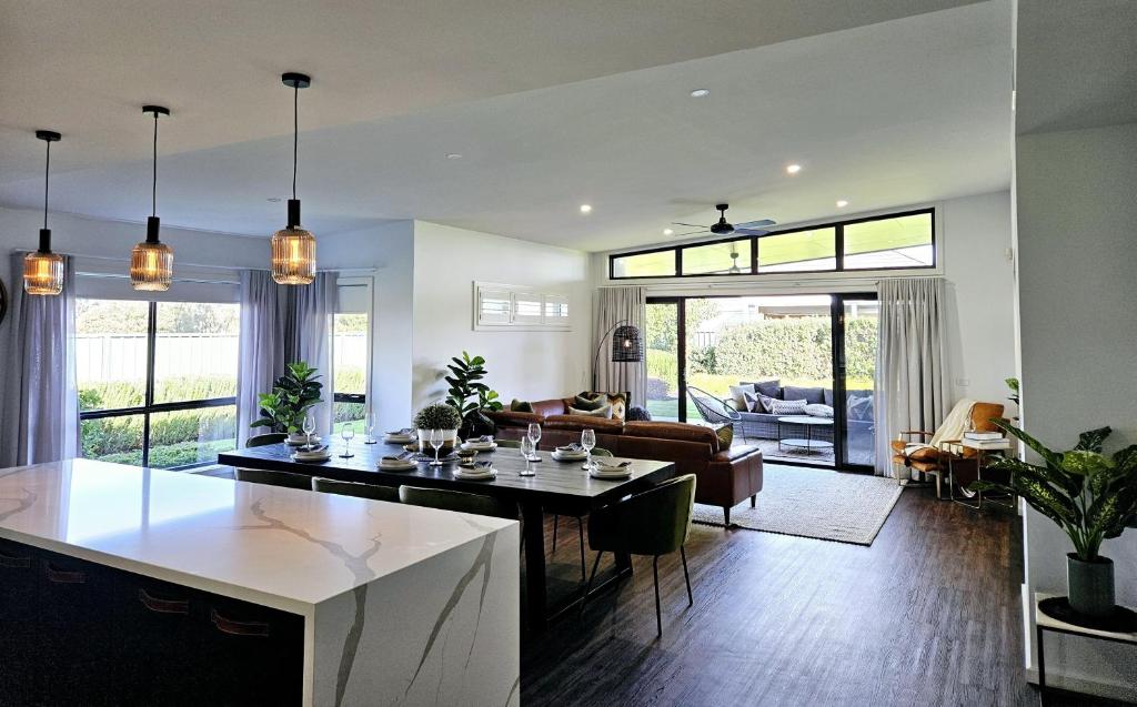 a kitchen and living room with a table and chairs at Charming on Cormorant in Kialla