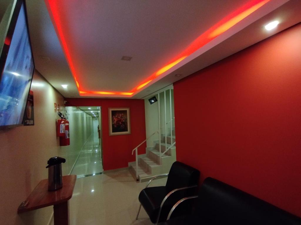 Cette chambre dispose d'un mur rouge avec des escaliers et d'une télévision. dans l'établissement Hotel motel Raiar do Sol santo Amaro, à São Paulo