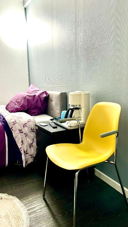 un bureau avec une chaise jaune à côté d'un lit dans l'établissement La Grey Room-Chambre Simple Privée - 700m Stade de France, à Saint-Denis