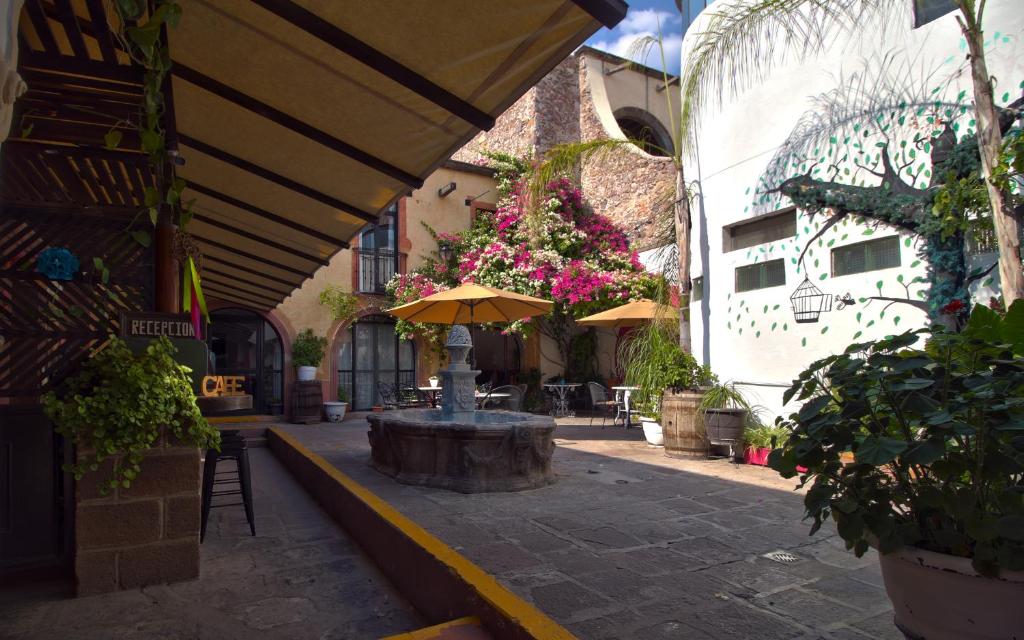un patio con sombrilla, mesas y flores en Hotel Punto 79, en San Miguel de Allende