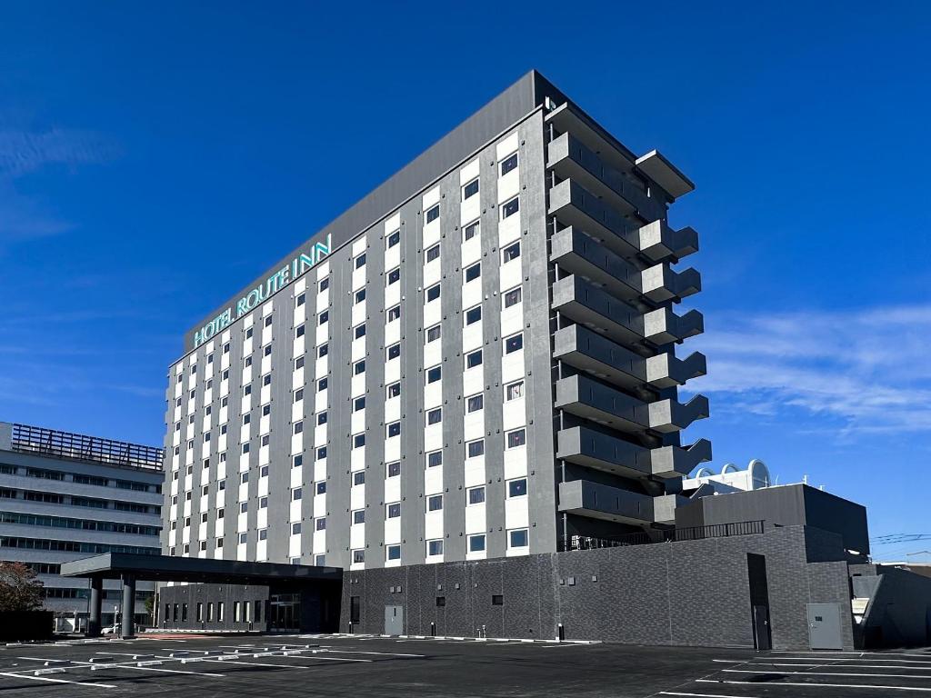 a large hotel building in a parking lot at Hotel Route Inn Miyakonojo in Miyakonozyō