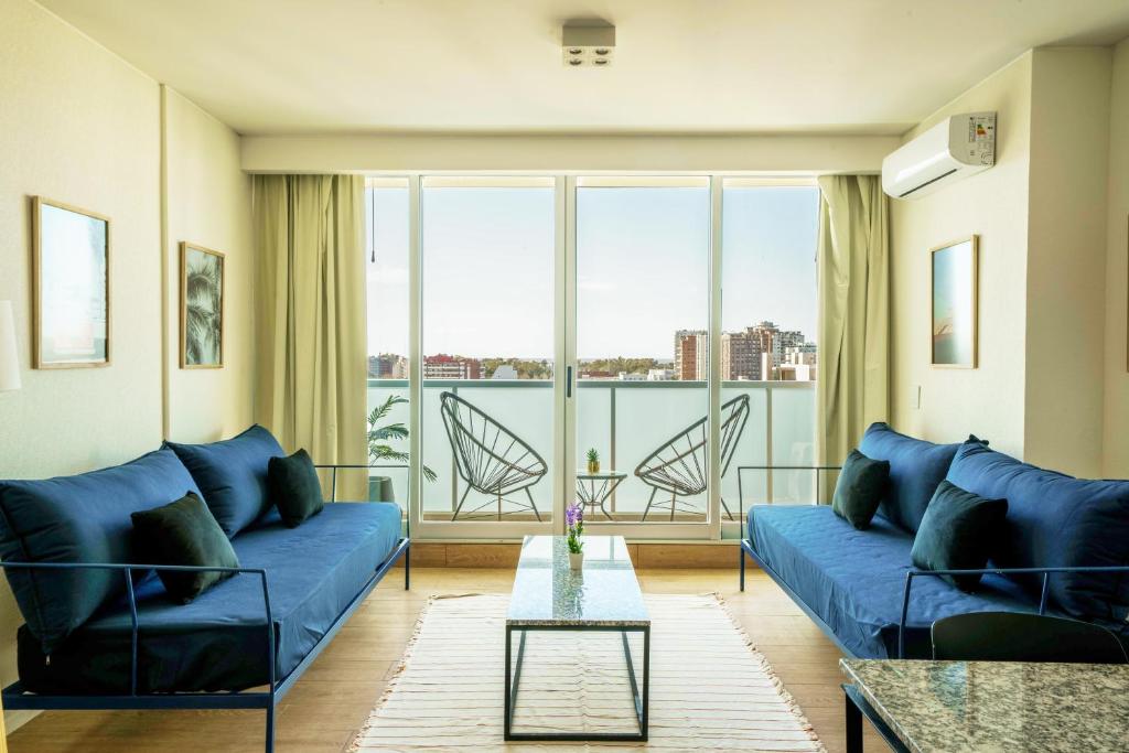 a living room with a blue couch and a glass table at Fliphaus Be Libertador - Lux 1 Bd 11-21 in Buenos Aires