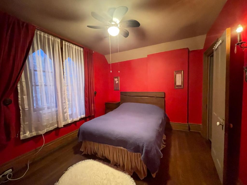 ein rotes Schlafzimmer mit einem Bett und einem Deckenventilator in der Unterkunft THE RED STAR ROOM A in Niagara Falls