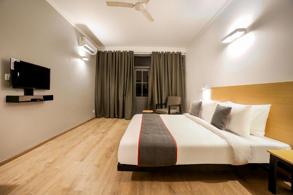 a hotel room with a bed and a tv at OYO Townhouse 330 DLF Phase-2 Near Leisure Valley Park in Gurgaon