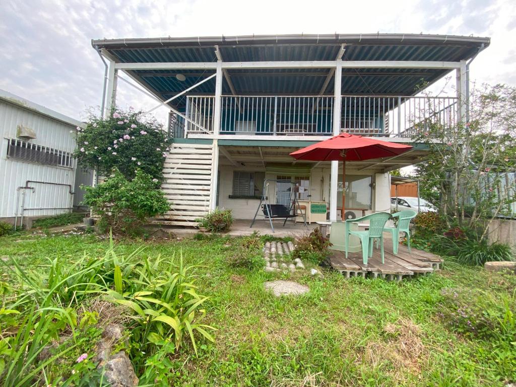 Casa con patio con sombrilla y sillas rojas en 海の丘 ステイ umioka stay, en Nakijin