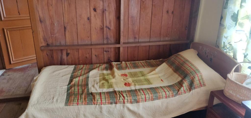 a bed in a room with a wooden wall at Mabie Homestay in Kohīma