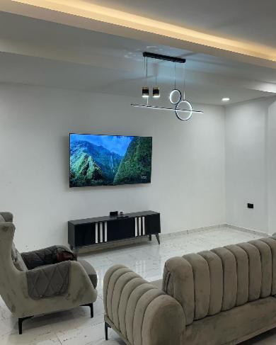 un soggiorno con 2 sedie e una TV a schermo piatto di REOs Smart Haven with Pool a Oblogo