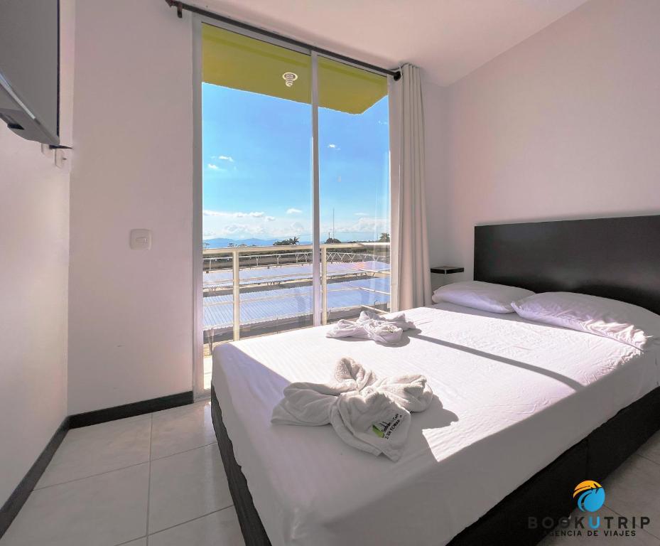 - une chambre avec un lit et une grande fenêtre dans l'établissement Aparthotel 2km Parque del Café BOOKUTRIP, à Montenegro