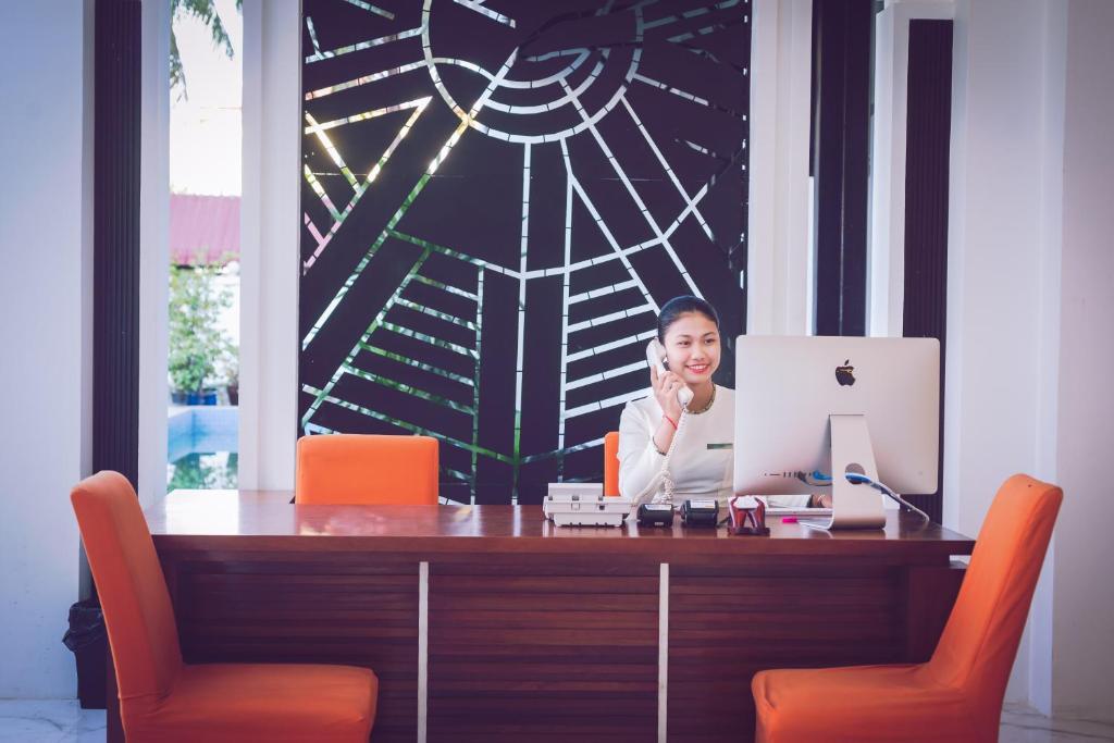 a woman sitting at a desk with a computer at Lotus Blanc Resort in Siem Reap