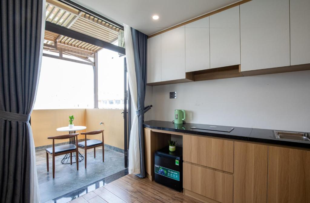 a kitchen with white cabinets and a table with chairs at FIRST Studio Hotel in Da Nang