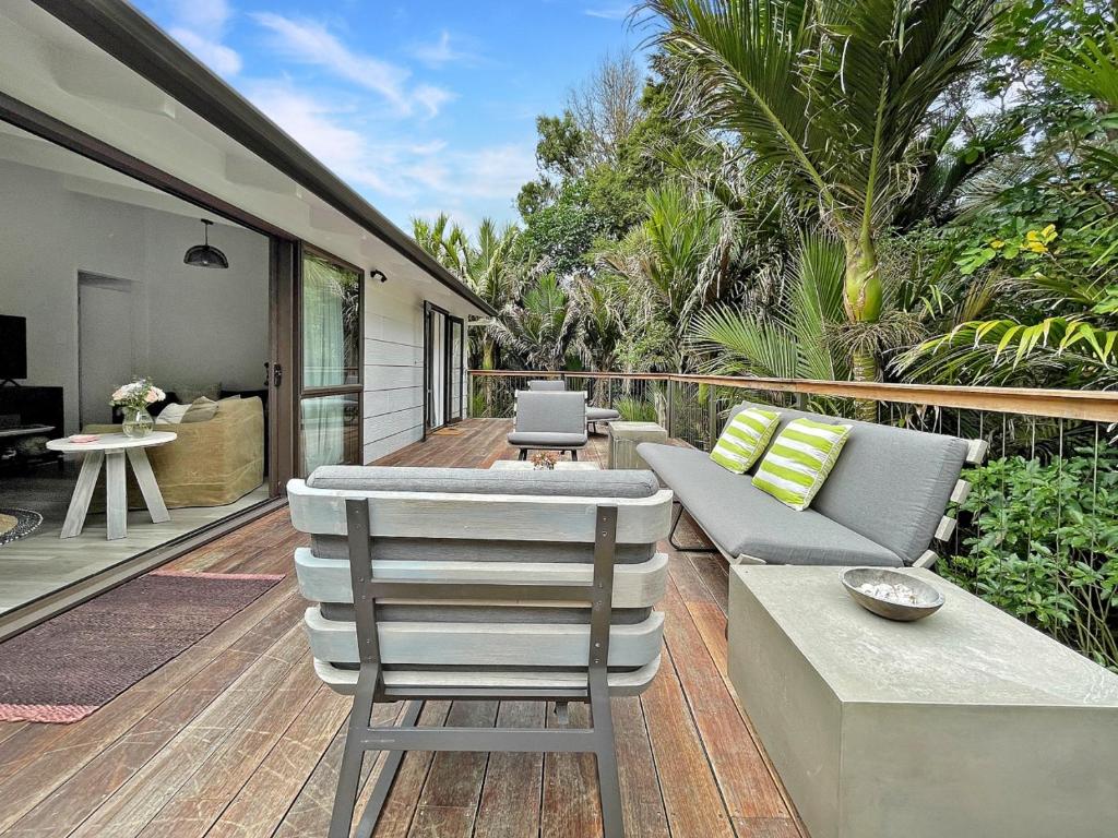 a patio with a couch and chairs on a deck at Tui Cottage - Waiheke Escapes in Onetangi