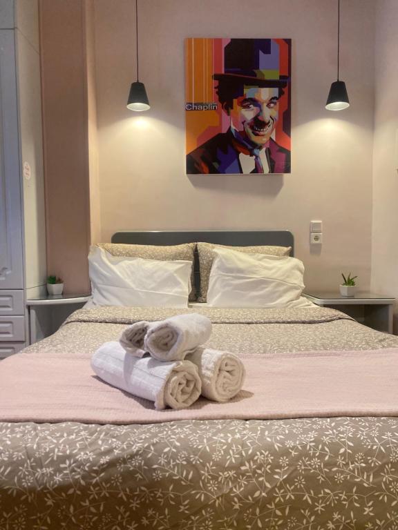 ein Bett mit Handtüchern und ein Gemälde eines Mannes in der Unterkunft ATHENS CITY THEMIS 4 in Athen