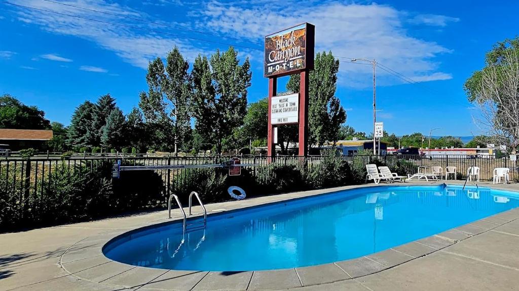 una piscina di fronte a un distributore di benzina con un cartello di Black Canyon Motel a Montrose