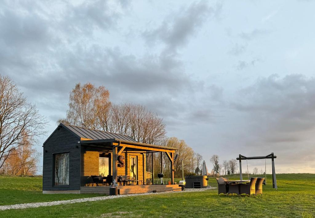 a small black house in a field with a playground at Salnēni in Vecpiebalga