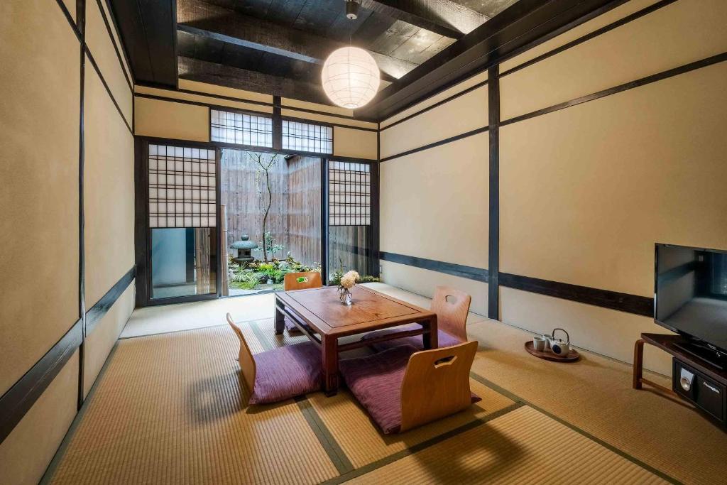 ein Zimmer mit Tisch und Stühlen und einem Fernseher in der Unterkunft Shobu an Machiya House in Kyoto