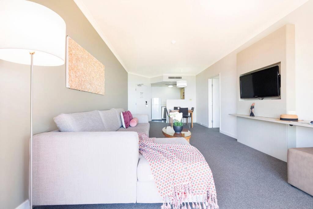 a living room with a white couch and a tv at Sky-high Waterfront Living across Two Apartments in Darwin