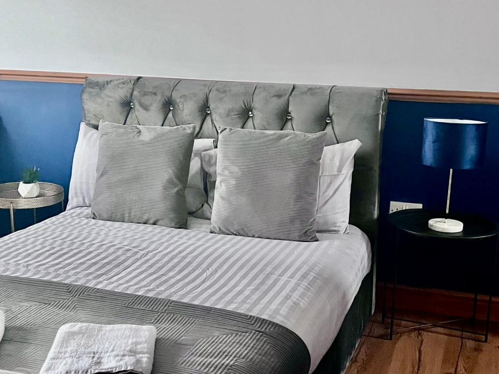 a bed with a gray headboard and pillows at Ashford Home - Spacious house close to Ashford International with ensuite and free parking in Ashford